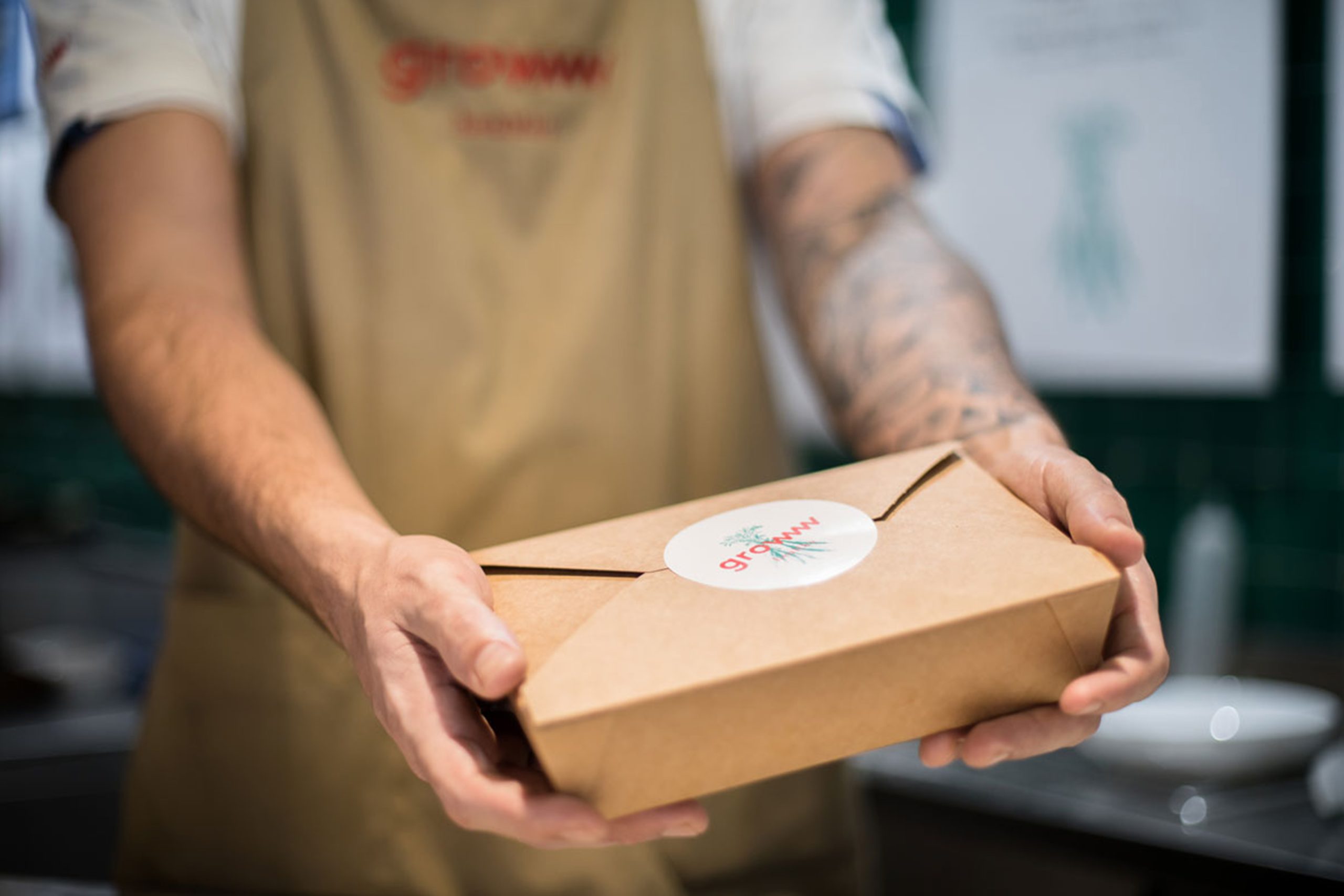 Employee handing over delivery box with branding sticker.